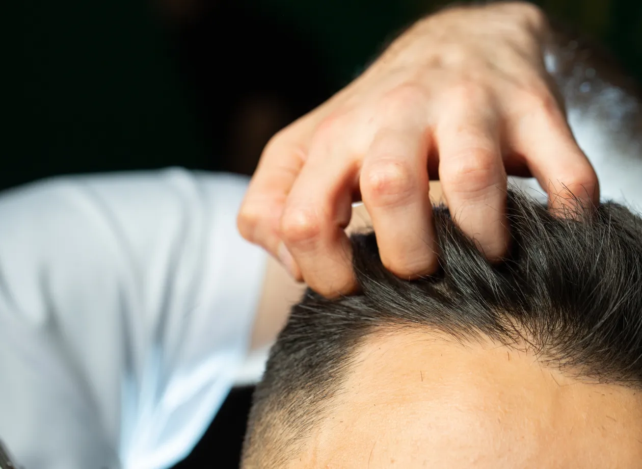 男性の頭皮を指でマッサージする手元