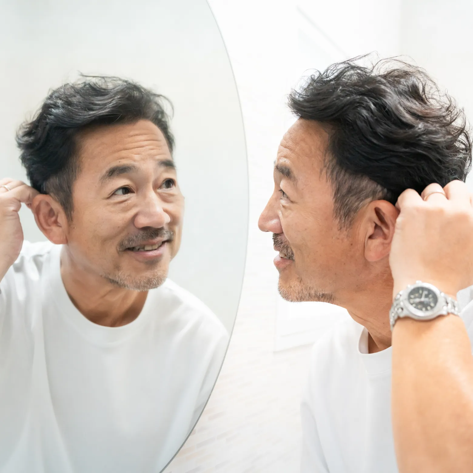 鏡を見ながら髪を整える中年男性